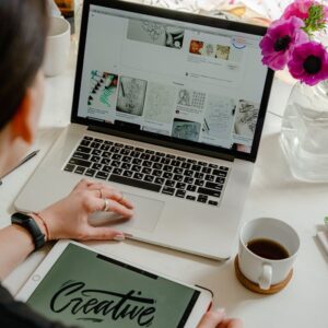 Creative work session featuring a woman using a tablet and laptop for design projects.