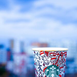 Colorful Starbucks cup against an urban backdrop with blurred city view.