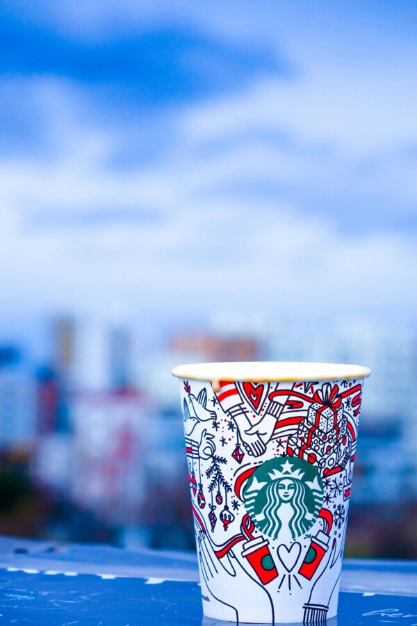 Colorful Starbucks cup against an urban backdrop with blurred city view.